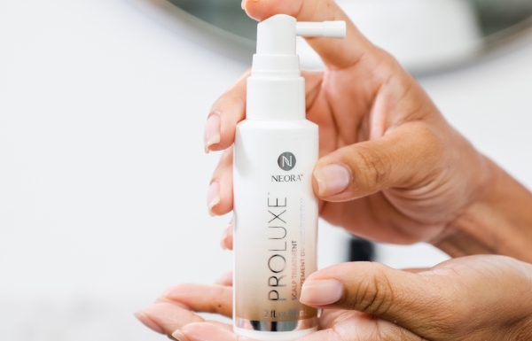 Image of a woman holding ProLuxe Scalp Treatment spray bottle.