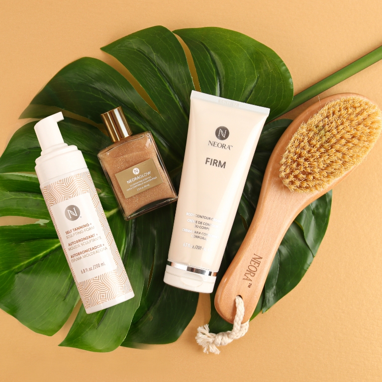 Image of 3-in-1 Self Tanning + Sculping Foam, NeoraGlow Illuminating Body Oil and Firm Body Contour Cream with a FREE Application Mitt and FREE Dry Brush with a leaf and flower behind it